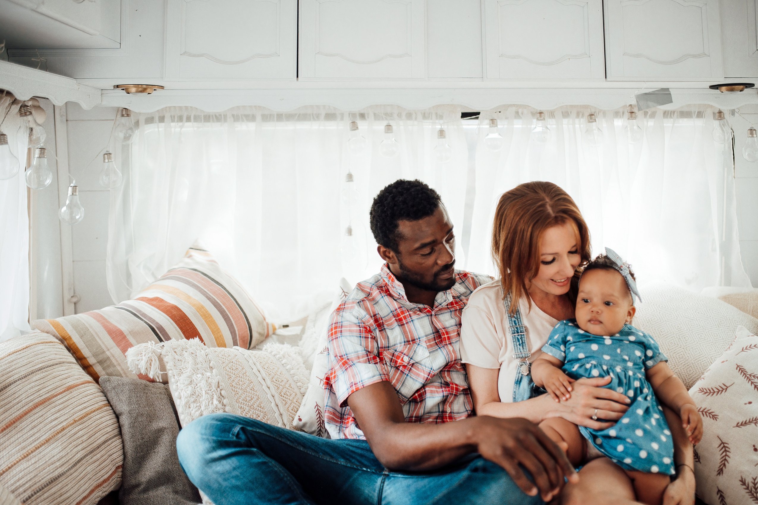 portrait-candid-happy-interracial-family-with-swarthy-daughter-sitting-together-rv-bed-day